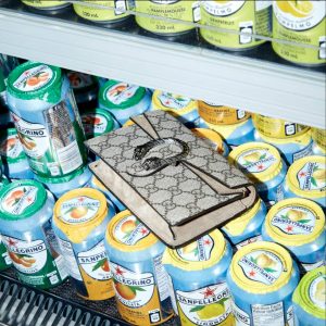 Gucci handbag on top of San Pellegrino Limonata in a refrigerated case.